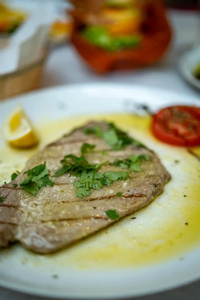 Plat de poisson grillé garni de persil et citron, typique de la cuisine portugaise