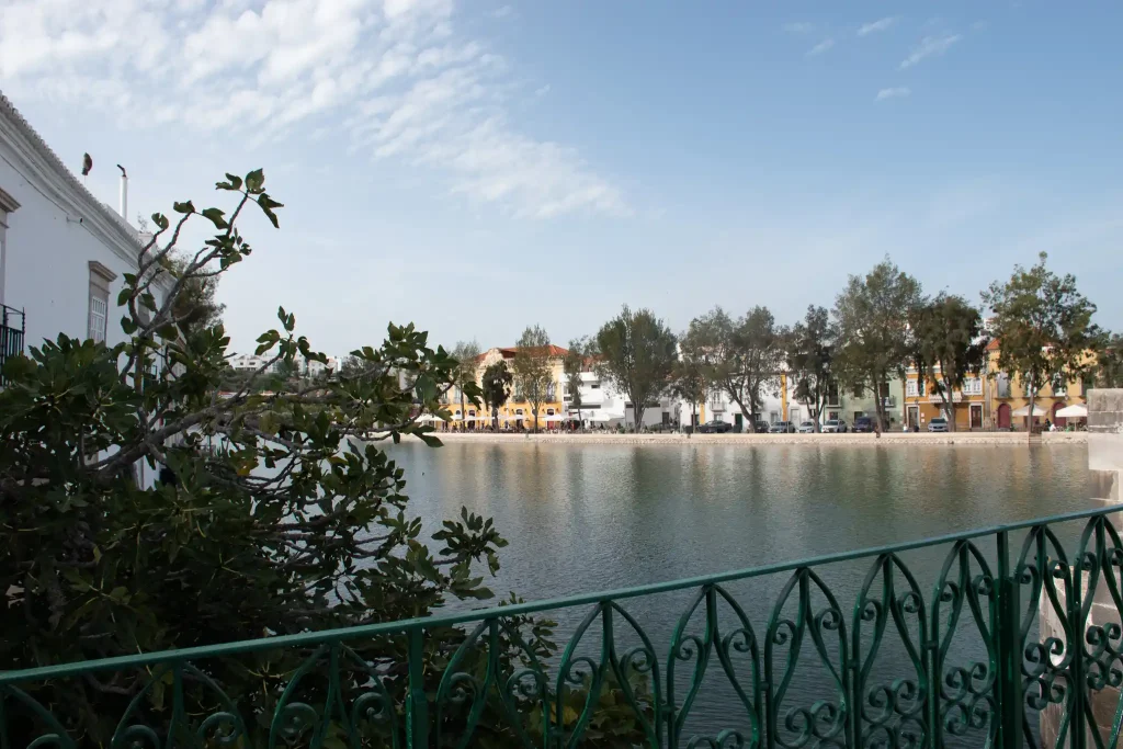 Vue sur le Rio Gilão à Tavira, Algarve, avec des bâtiments colorés en arrière-plan et ciel bleu.