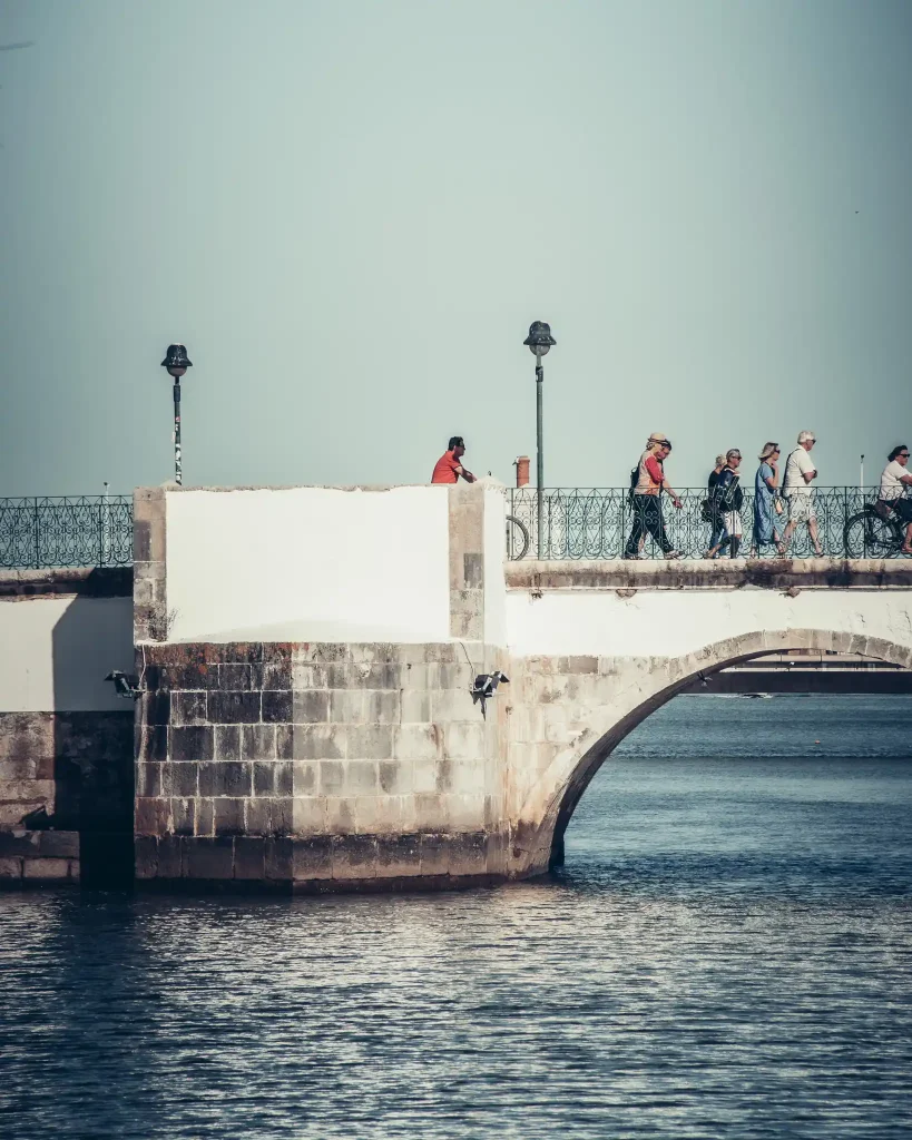 Pont romain de Tavira avec passants, ambiance paisible, ciel bleu clair, Algarve, Portugal.
