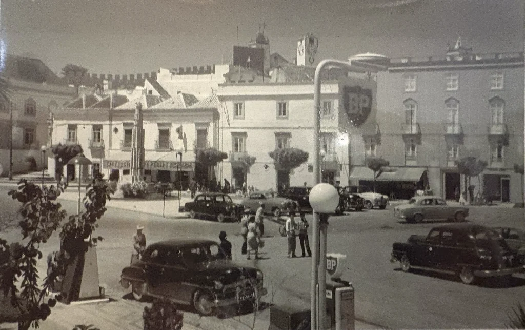 Place centrale de Tavira, Portugal, avec voitures anciennes et bâtiments historiques sous un ciel dégagé.