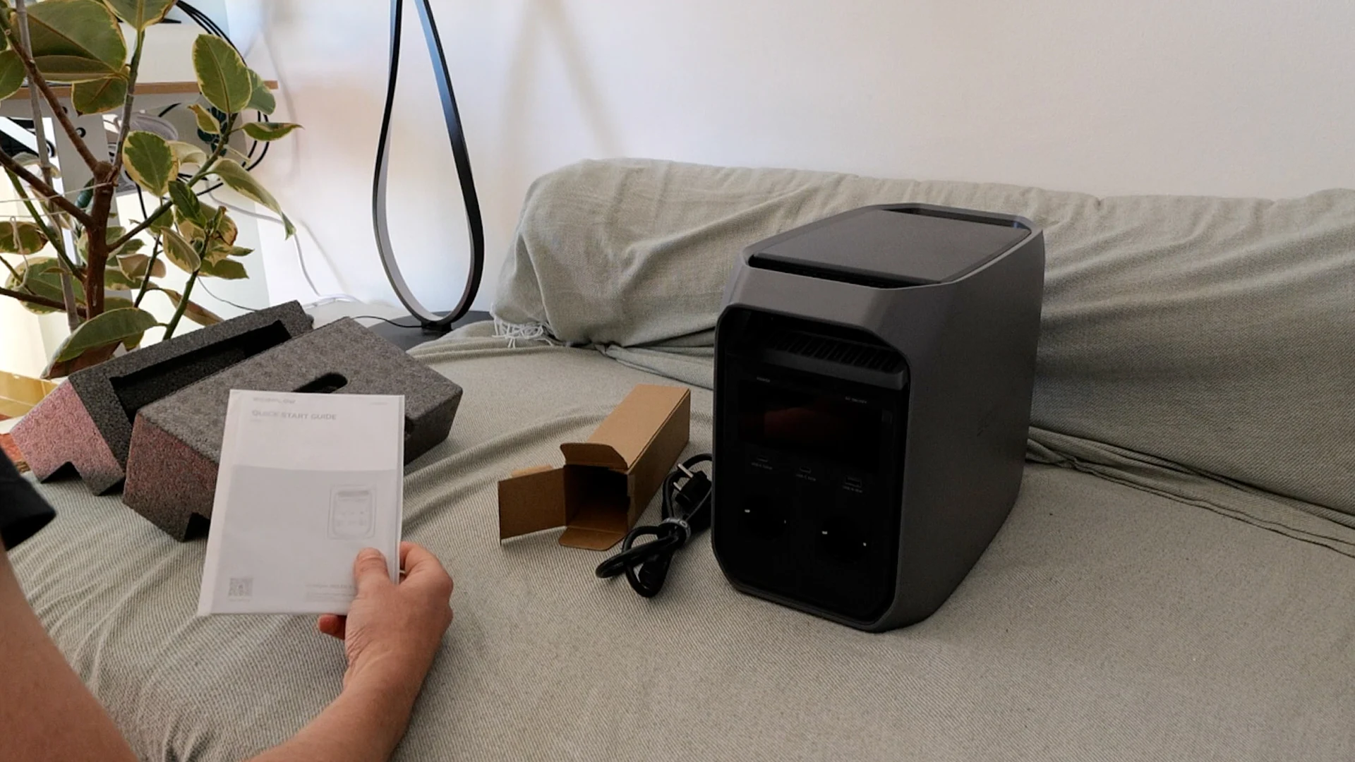 Testing the EcoFlow Delta 3 Classic generator on a sofa, manual in hand.