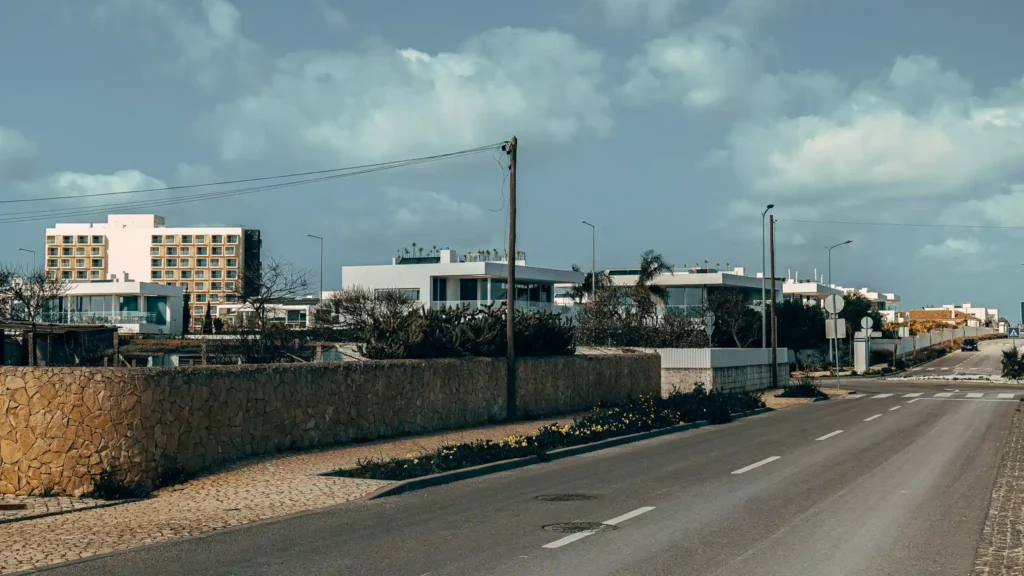 Road lined with modern buildings under a cloudy sky in Lagos, Portugal.