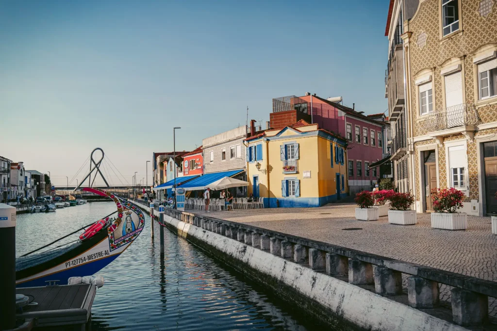 Aveiro canal with colorful houses and traditional moliceiro boats under a blue sky.