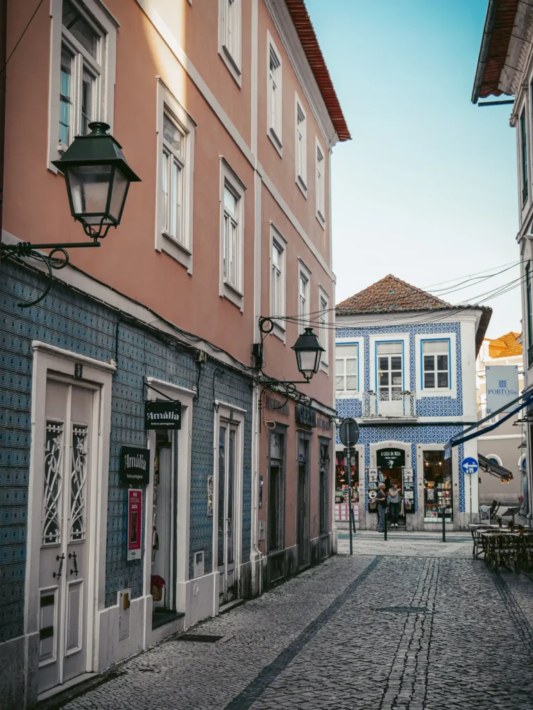 Picturesque cobblestone street in Aveiro, Portugal, lined with colorful buildings and old lampposts.