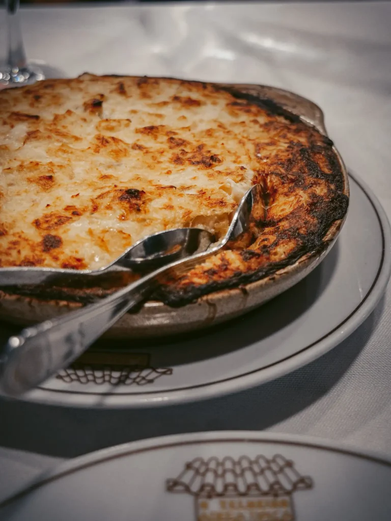 Plat de bacalhau com natas doré, servi dans un restaurant typique à Aveiro, ambiance chaleureuse et conviviale.