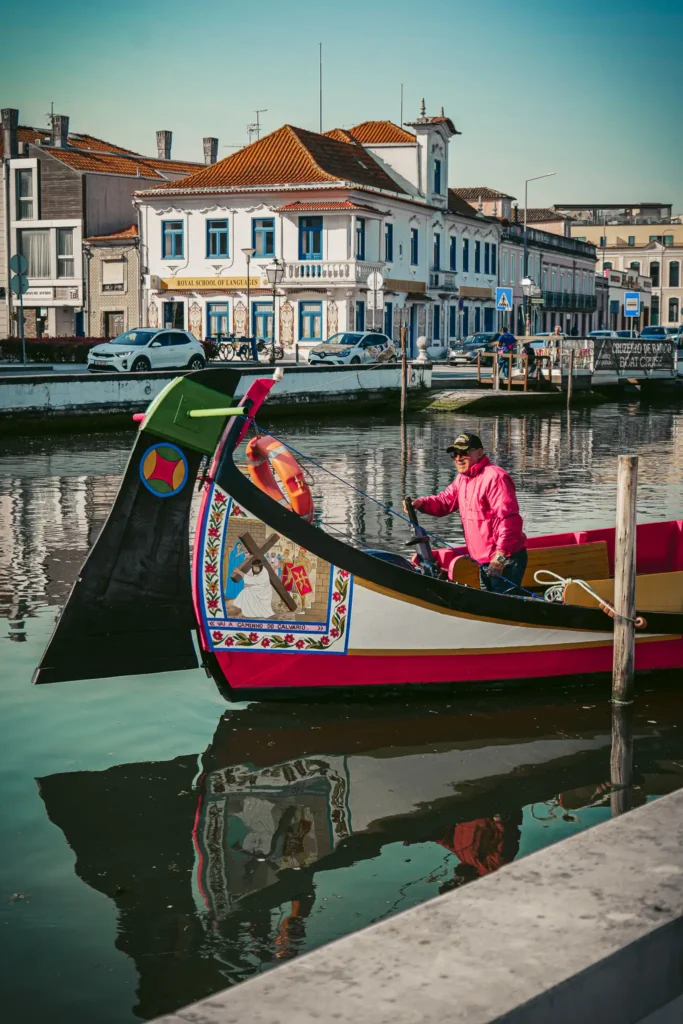 Aveiro canal with a man in a colorful gondola, historic buildings in the background, peaceful atmosphere.