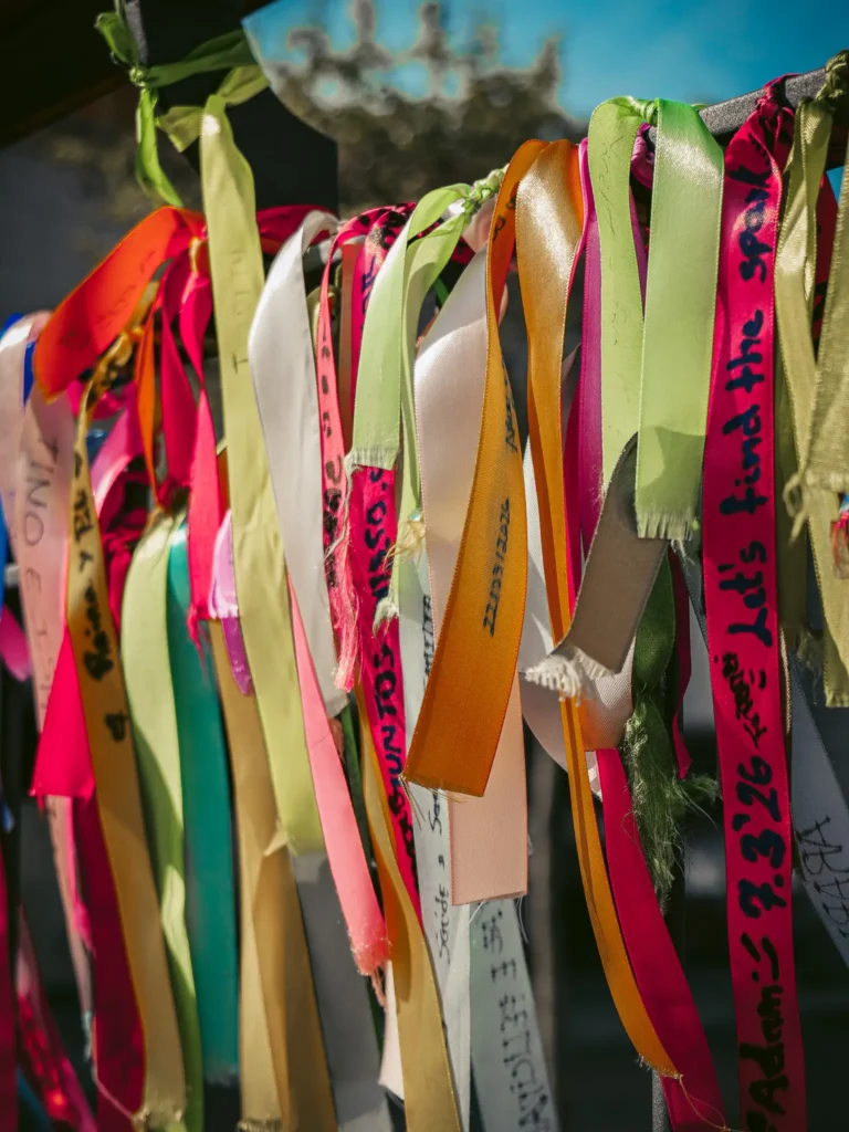 Colorful ribbons hanging in Aveiro, Portugal, vibrant under the sun, symbolizing hopes and wishes of visitors.