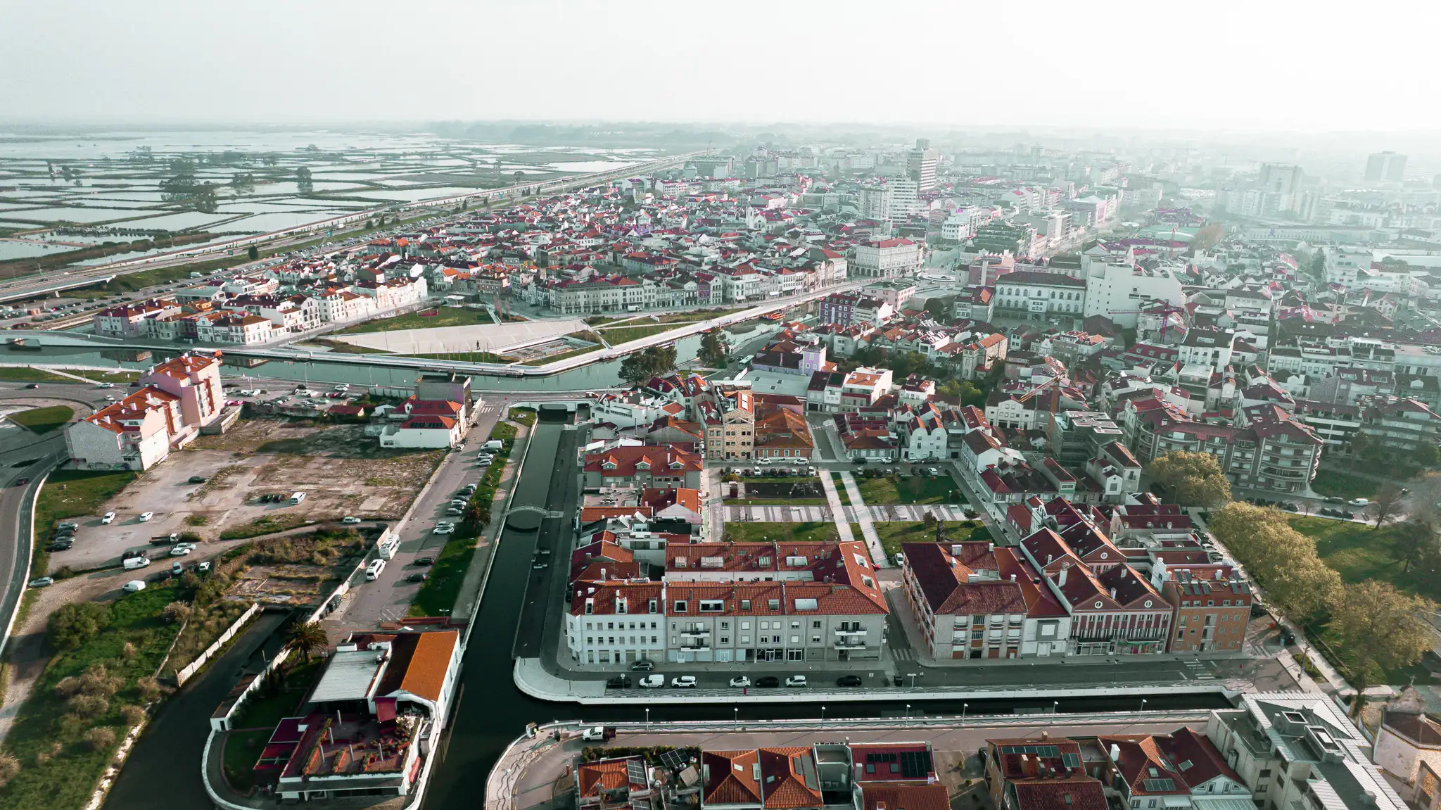 Aerial view of Aveiro, Portugal, with its picturesque canals and red roofs under a clear sky.