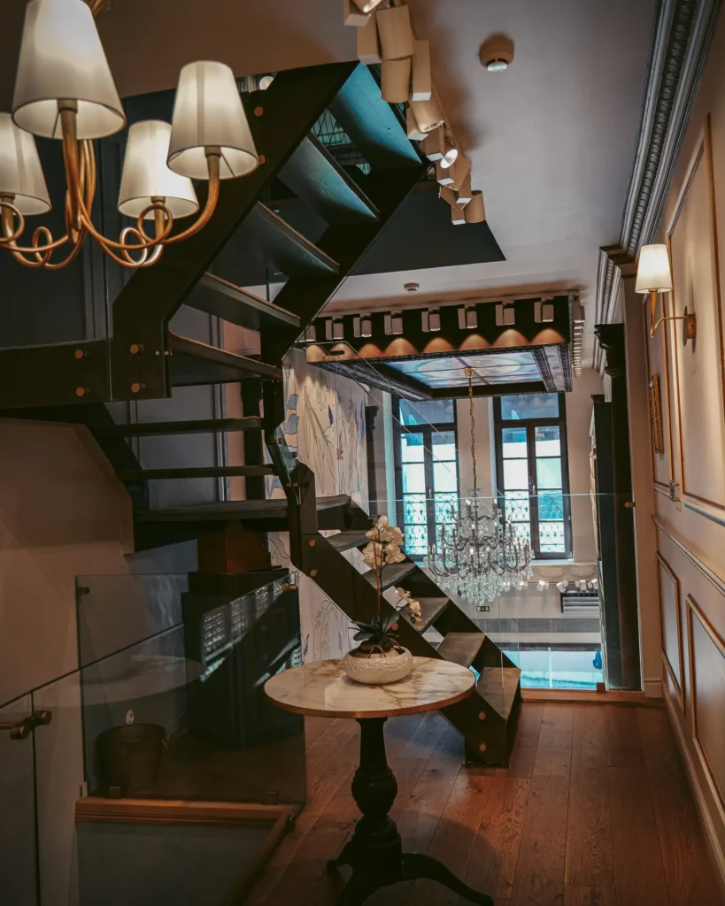 Elegant interior staircase at Confeitaria Peixinho, Aveiro, Portugal, with chandelier and wooden table.