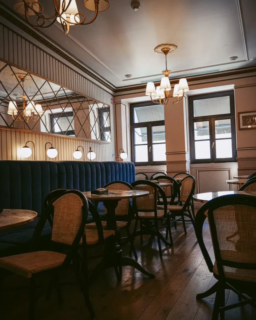 Elegant interior of Confeitaria Peixinho in Aveiro, Portugal, with wooden tables and classic light fixtures.