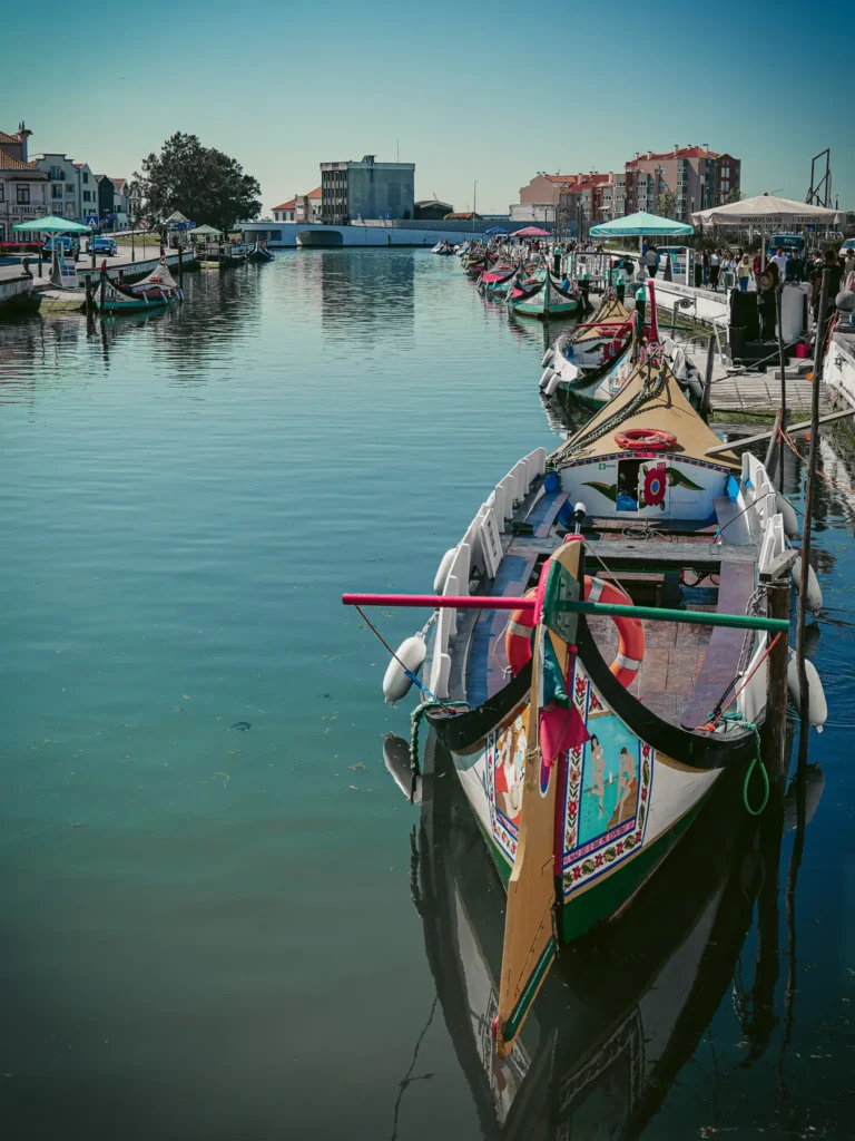 Canals of Aveiro with colorful boats under a blue sky, peaceful and picturesque atmosphere.