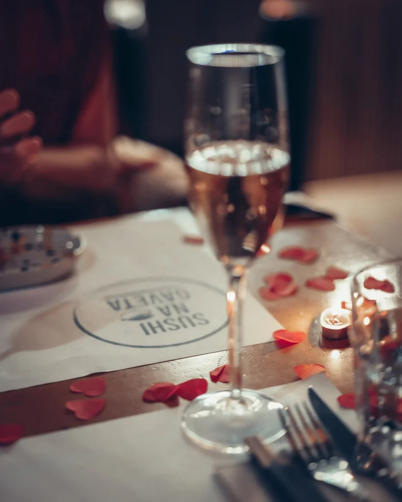 Verre de vin pétillant sur table décorée de pétales rouges au restaurant Sushi na Gaveta