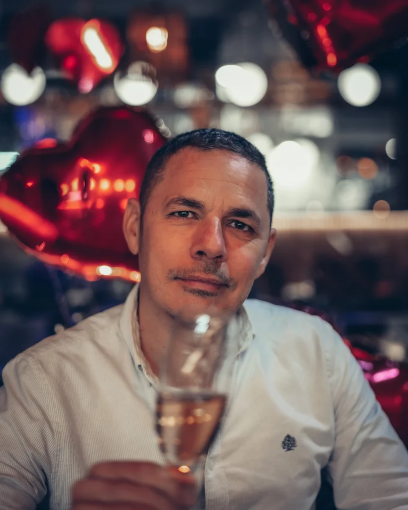 Xavier enjoying champagne at Sushi na Gaveta, Tavira, with heart-shaped balloons in the background.