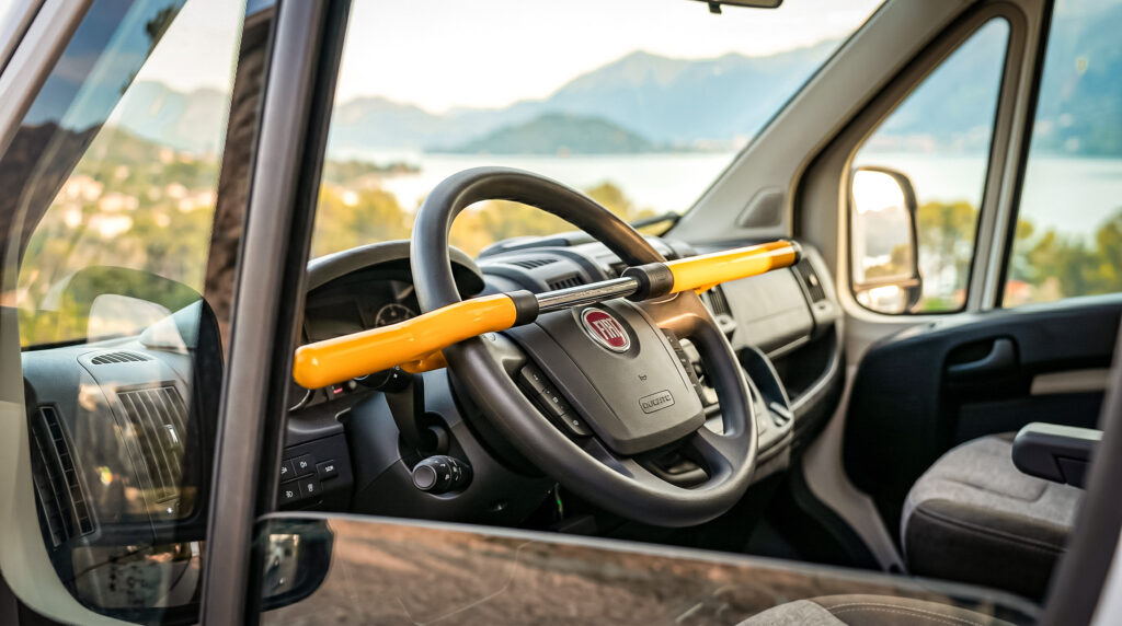 Steering wheel lock installed in a converted van with a view of a lake and mountains in the background.