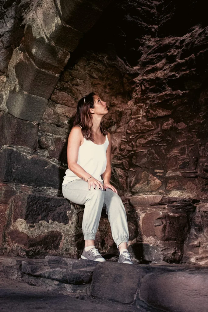 Caroline sitting on a stone in an alcove of Dunnottar Castle in Scotland