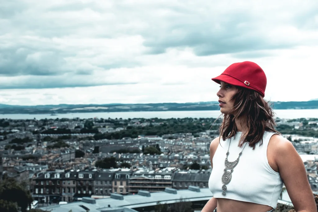 Caroline in a red hat in front of the Edinburgh panorama with the North Sea in the background