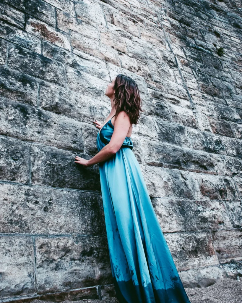 Caroline in a long blue dress near an ancient stone wall in St Andrews, Scotland