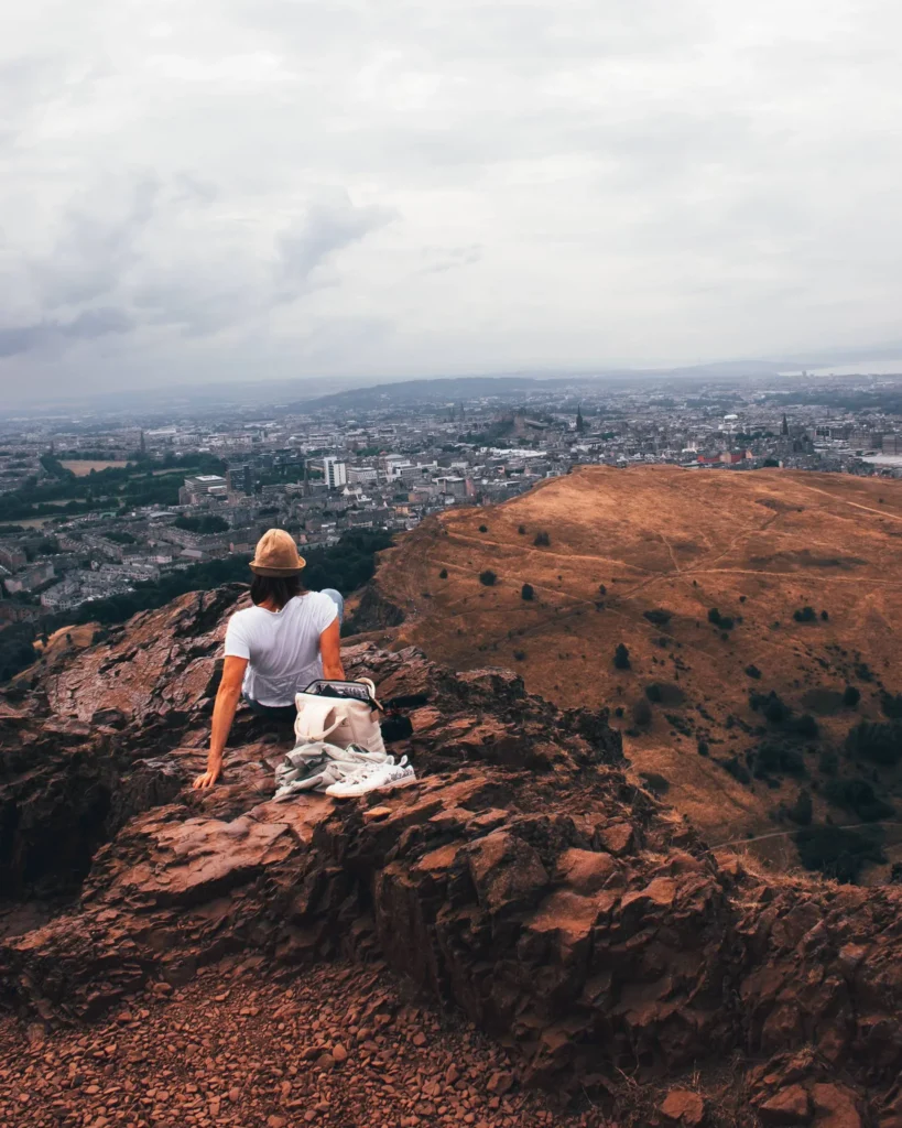 Caroline sitting on the rocks at the top of Arthur's Seat overlooking Edinburgh