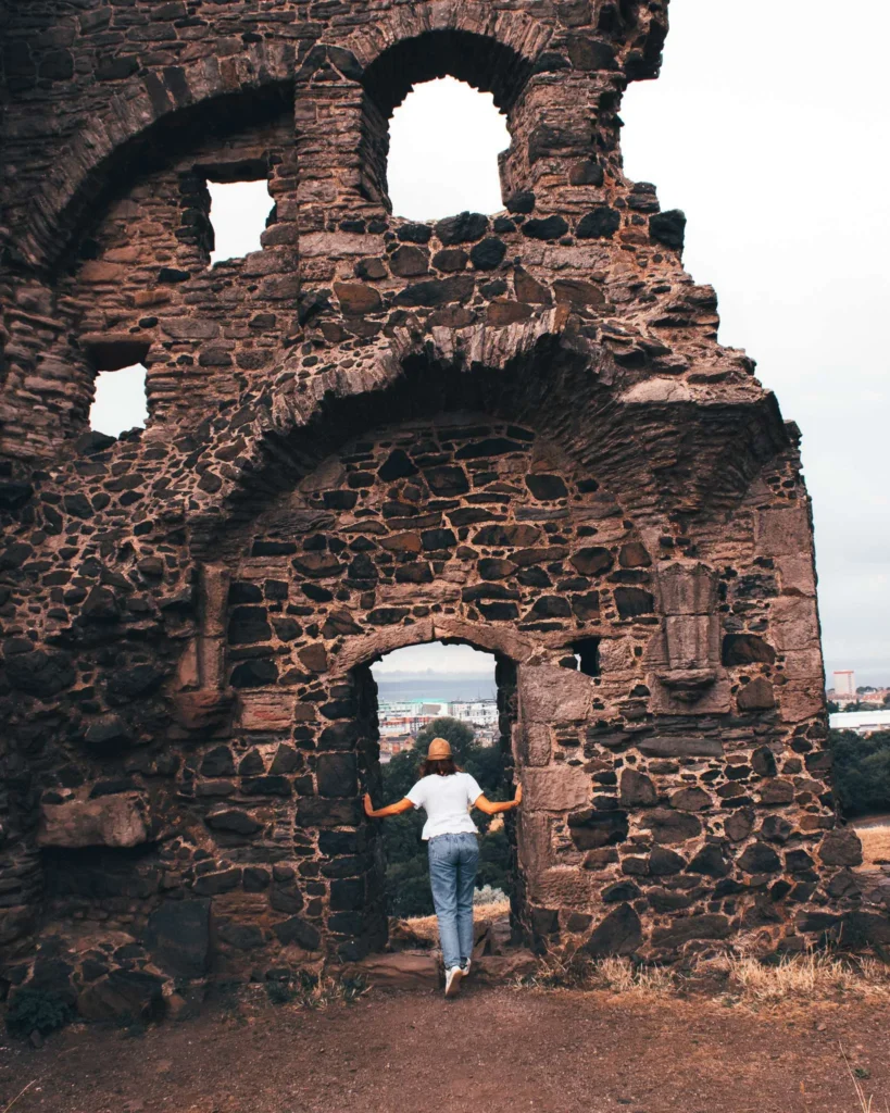 Caroline seen from behind in front of a stone ruin on Arthur's Seat hill