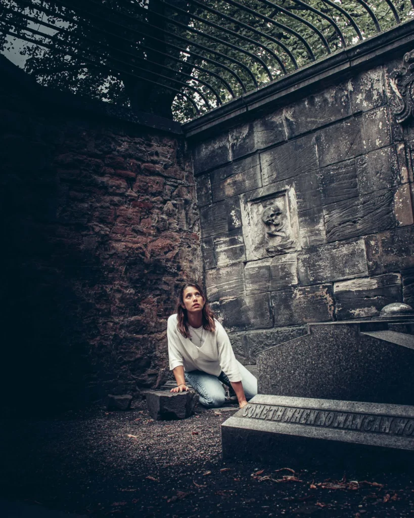 Caroline kneeling by an ancient grave in Greyfriars cemetery