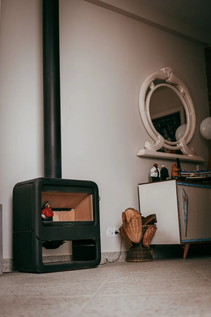 Modern wood stove in a decorated living room, with an oval mirror, a wicker wood basket, and a retro sideboard, in Fuseta, Algarve.