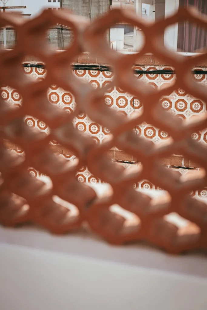 Portuguese orange and white tiled pattern seen through a lattice, outdoor atmosphere in Fuseta, Algarve.