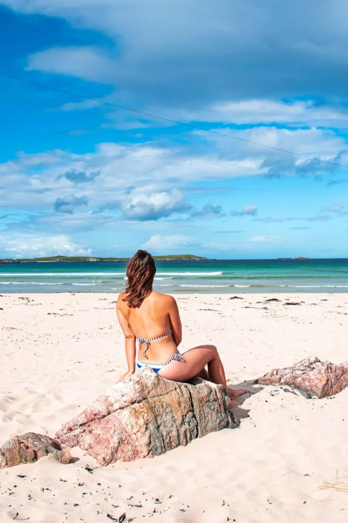 Caroline sitting on a rock at Sangomore beach in Durness