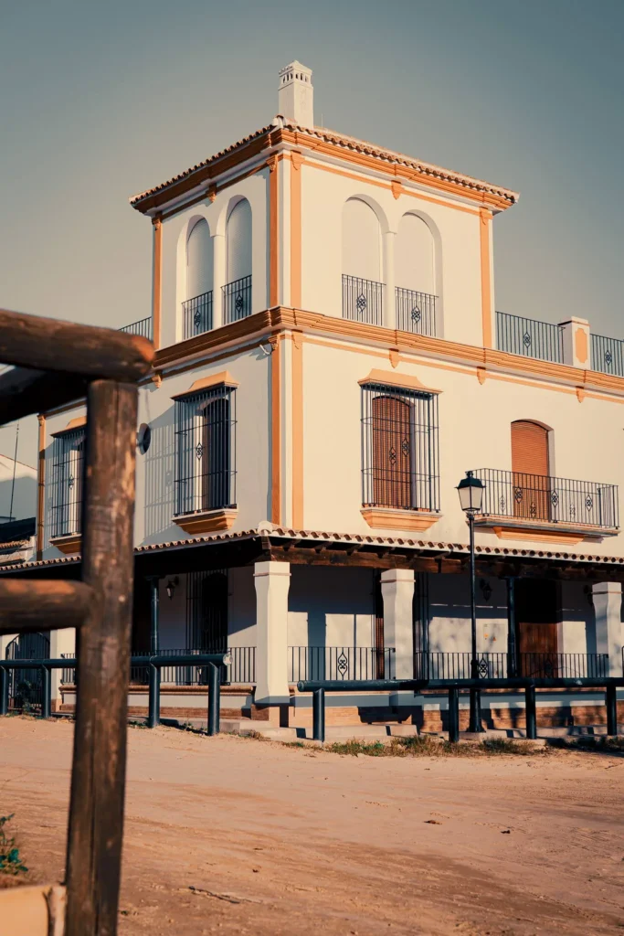 Traditional Andalusian building in El Rocio, with white facades and closed shutters under the late winter afternoon light.