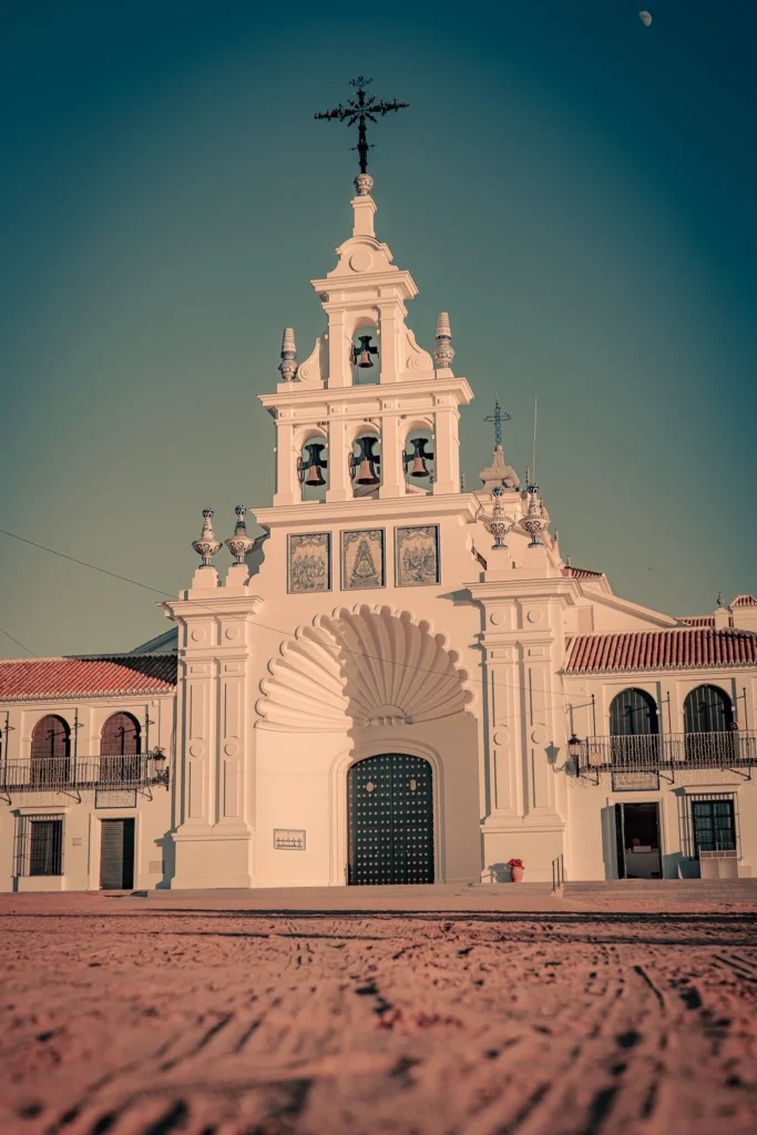 Facade of the Santuario Nuestra Señora del Rocío under a clear sky in Andalusia, Spain, with late afternoon light and no visible passersby.