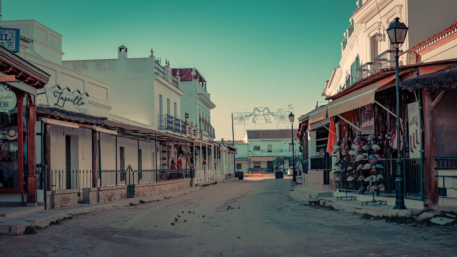 Main street of El Rocio in Andalusia, lined with white houses and traditional shops, calm atmosphere in winter with no visible human presence.