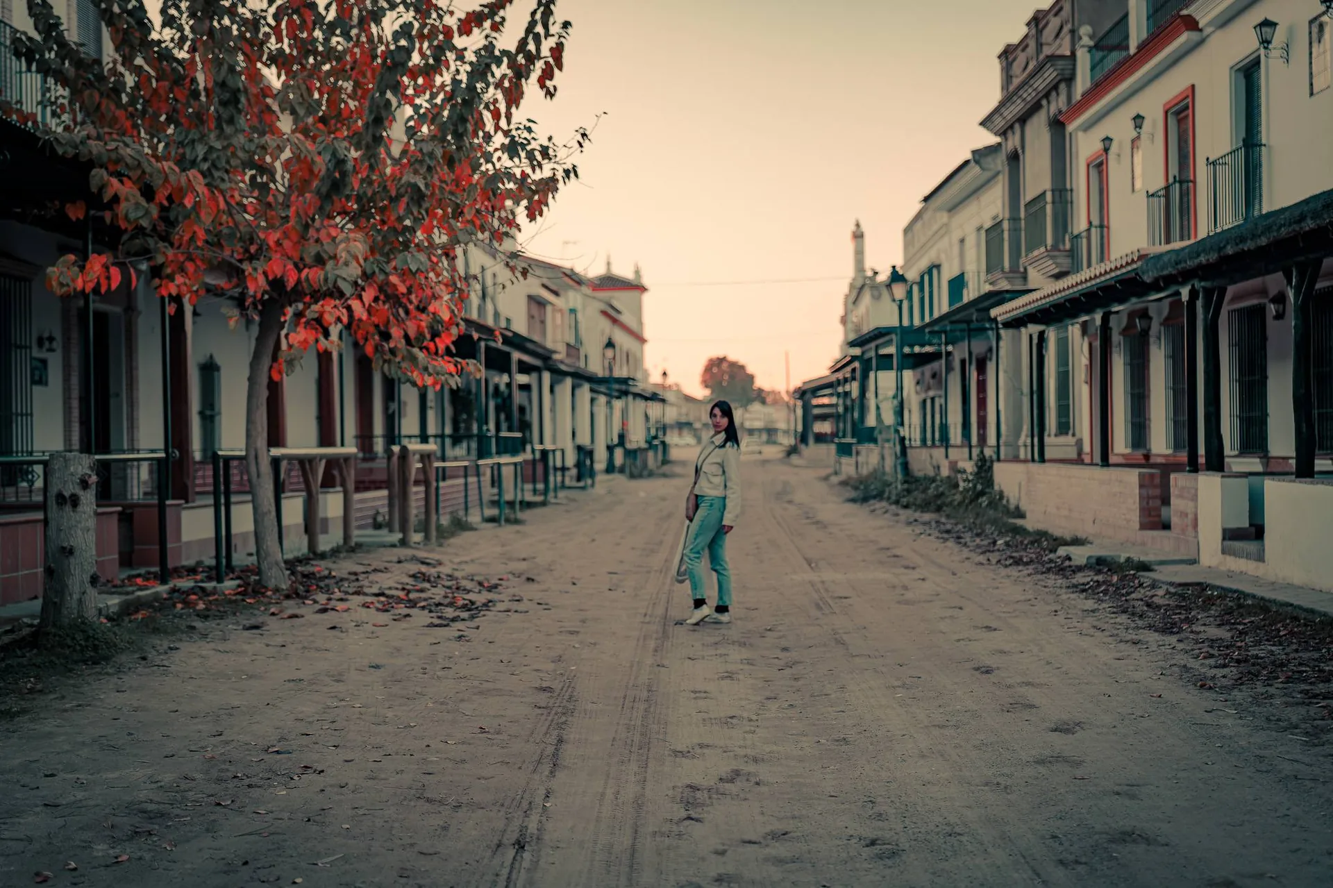 Caroline walks down a deserted street lined with traditional houses in El Rocio, Andalusia, at dusk in December.