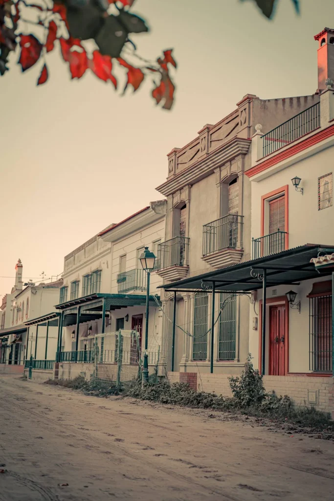Traditional house facades lining a sandy street in El Rocio, Andalusia, under the soft light of late afternoon in December.