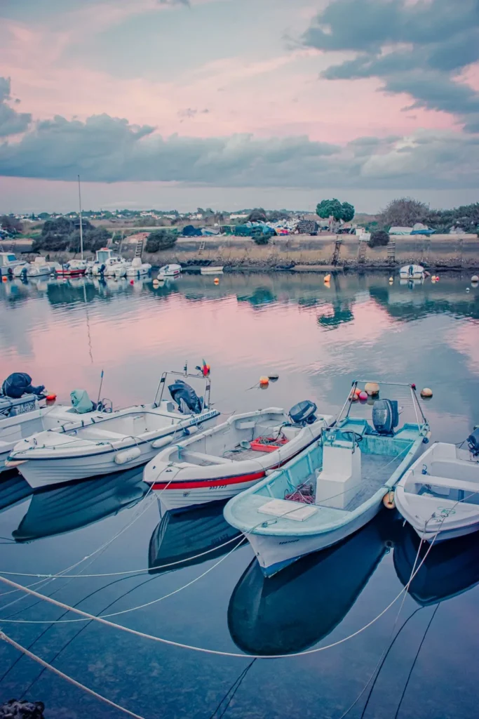 Barques de pêche amarrées dans un petit port à Fuseta, Algarve, sous un ciel de fin de journée en novembre 2022.