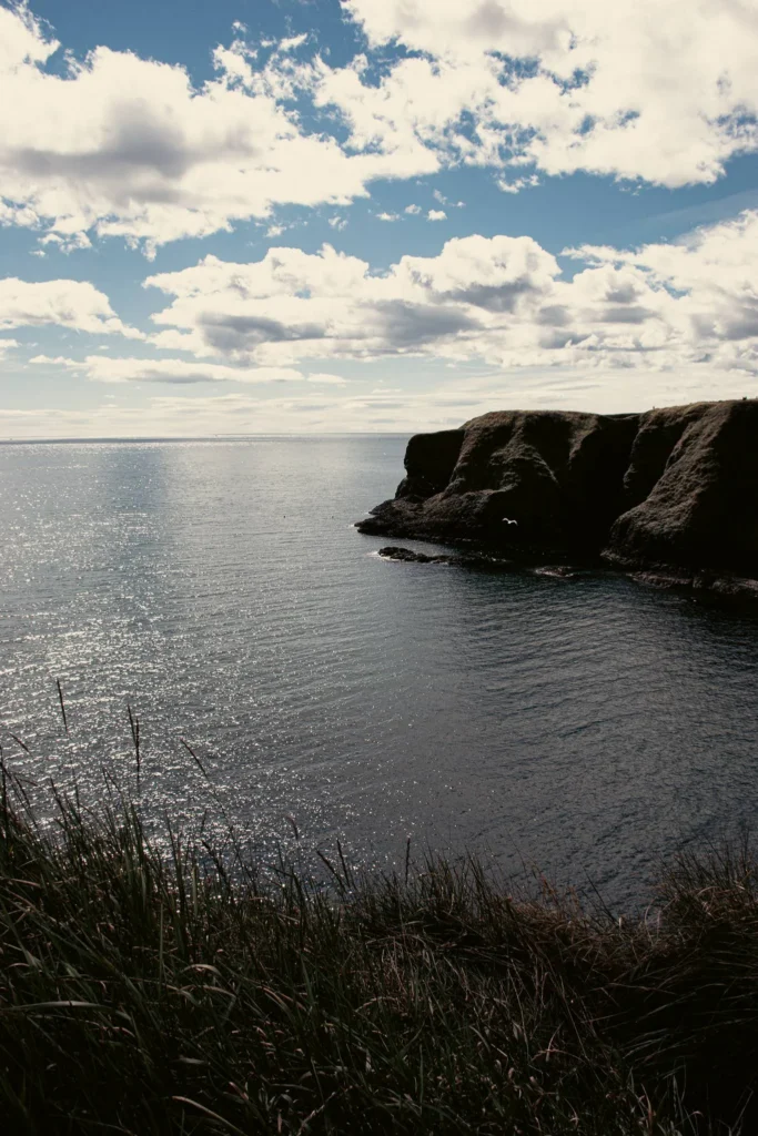 View of the sea and the cliffs of Dunnottar in Scotland under a partly cloudy sky