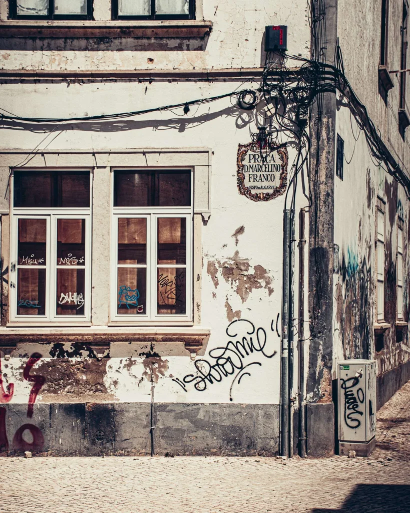 Façade d'un bâtiment ancien à Faro, Algarve, avec des murs abîmés et des graffitis, sous une lumière de journée d'automne.