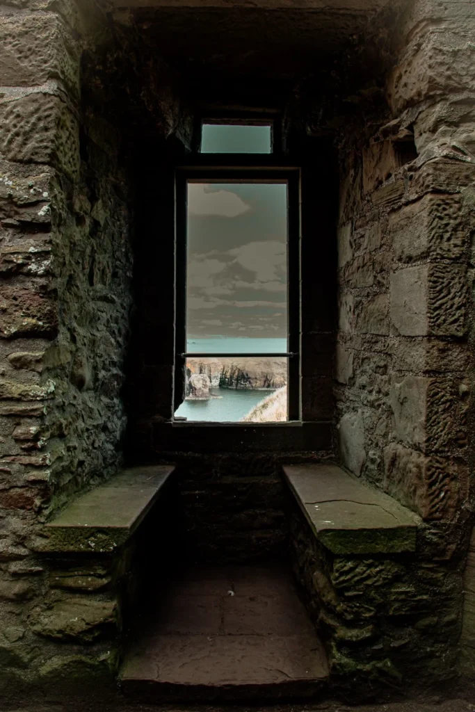 View of the sea through a stone window of an old building in Dunnottar