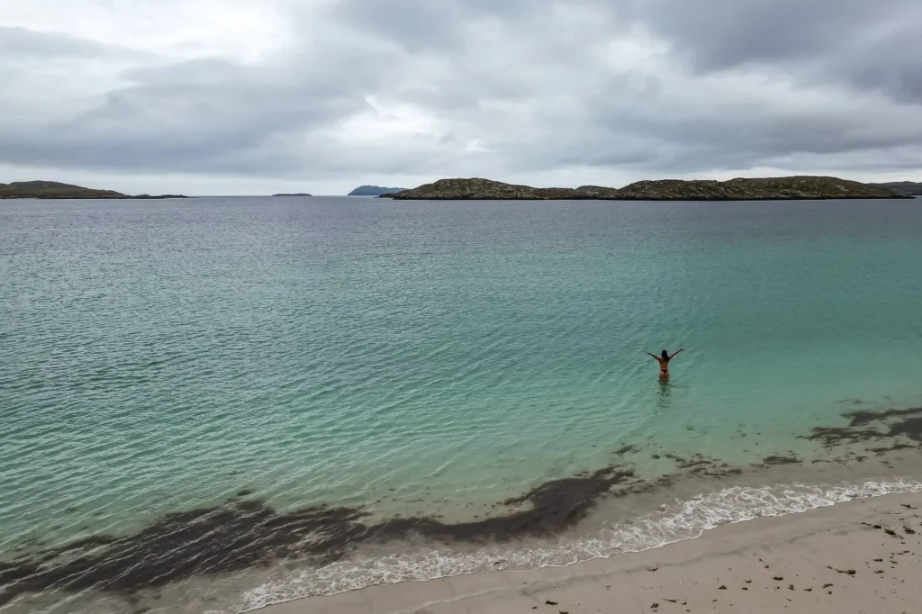 Caroline swims at the beach on Harris Island under a cloudy sky.