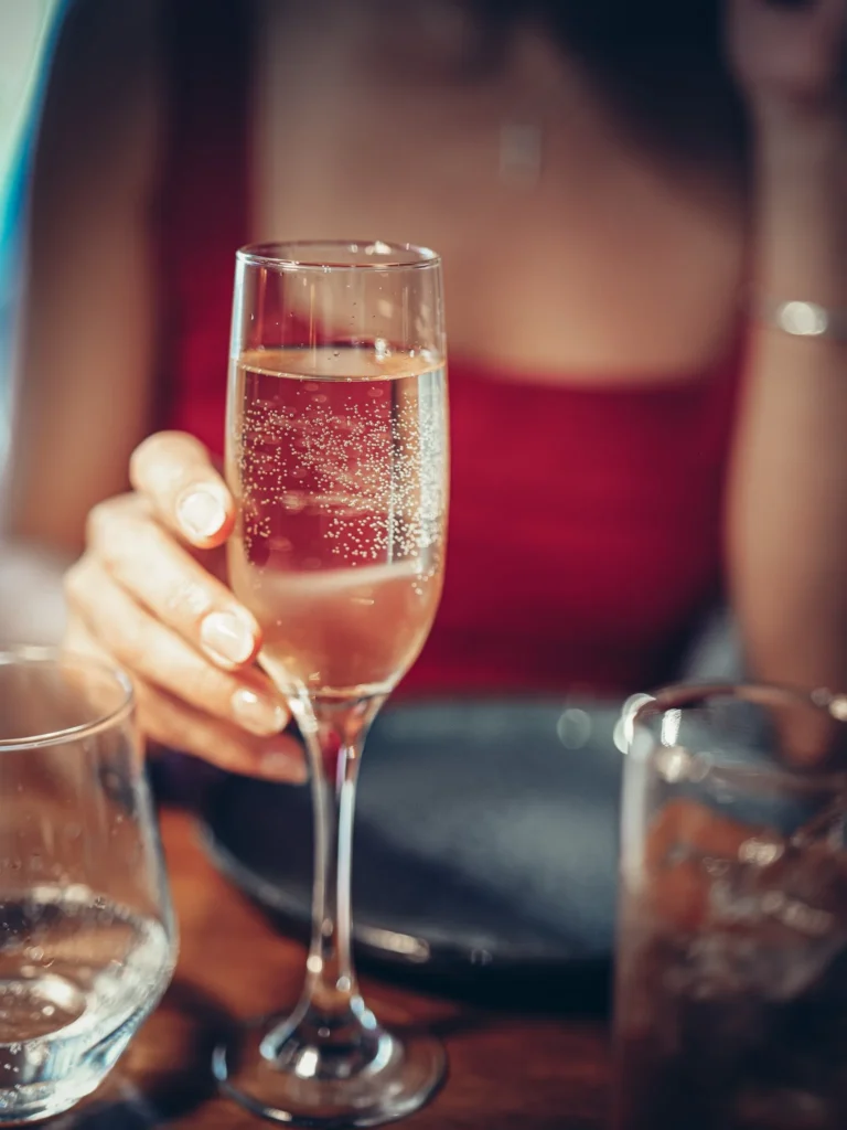 Caroline hält ein Glas Schaumwein (epumante) an einem Tisch im Restaurant 8 Tapas in Faro, mit einer sommerlichen und entspannten Atmosphäre.