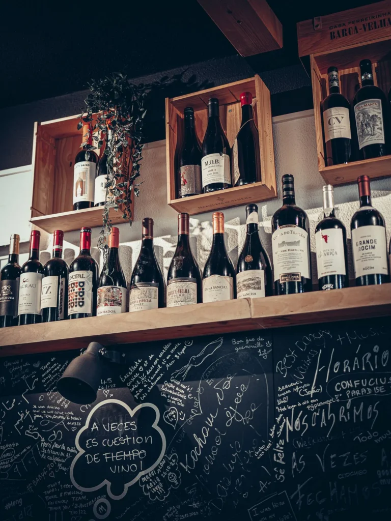 Tapas-Barregal in Faro mit einer Auswahl an ausgestellten portugiesischen Weinen und einer Schiefertafelwand, die mit handschriftlichen Notizen bedeckt ist.