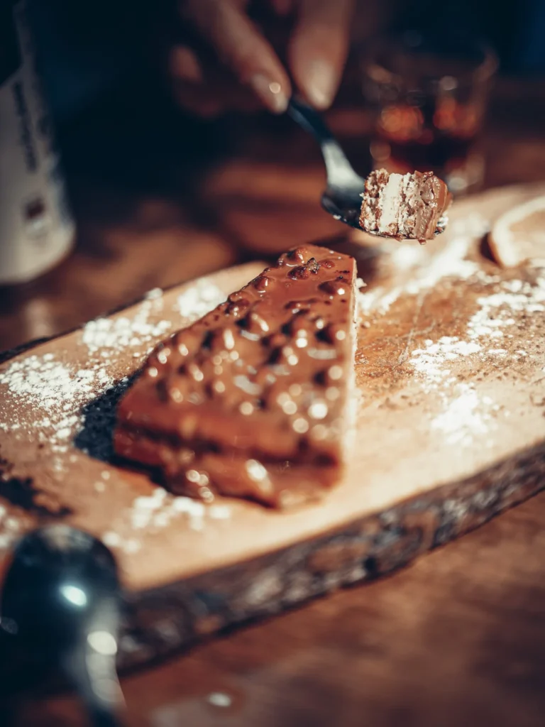 Stück Toblerone Schokoladenkuchen, serviert auf einem Holzbrett in einem Restaurant in Faro, Algarve, mit einer gemütlichen Atmosphäre.
