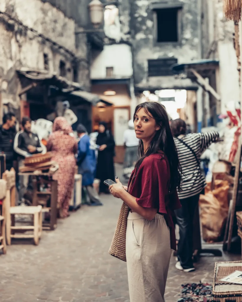 Caroline exploring a bustling souk in Marrakech, surrounded by artisan shops and passersby.