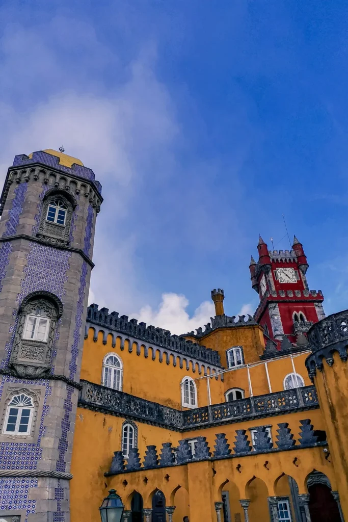Colorful facades of the National Palace of Pena in Sintra, with its tower adorned with tiles and its romantic architecture under a blue sky in February 2022.