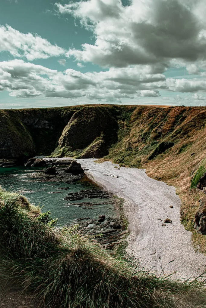 Small pebble beach surrounded by green cliffs near Dunnottar