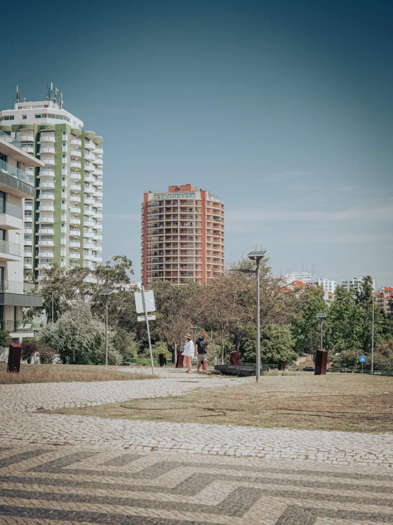 Modern residential buildings in Portimao, Algarve, with green spaces and a paved driveway under a clear sky.
