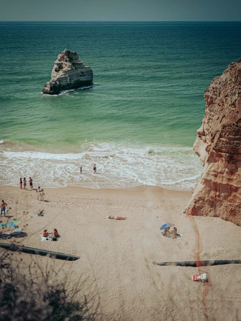 Sandy beach at the foot of golden cliffs in Portimao, Algarve, with a few people enjoying the sun and the Atlantic Ocean on May 24, 2026.
