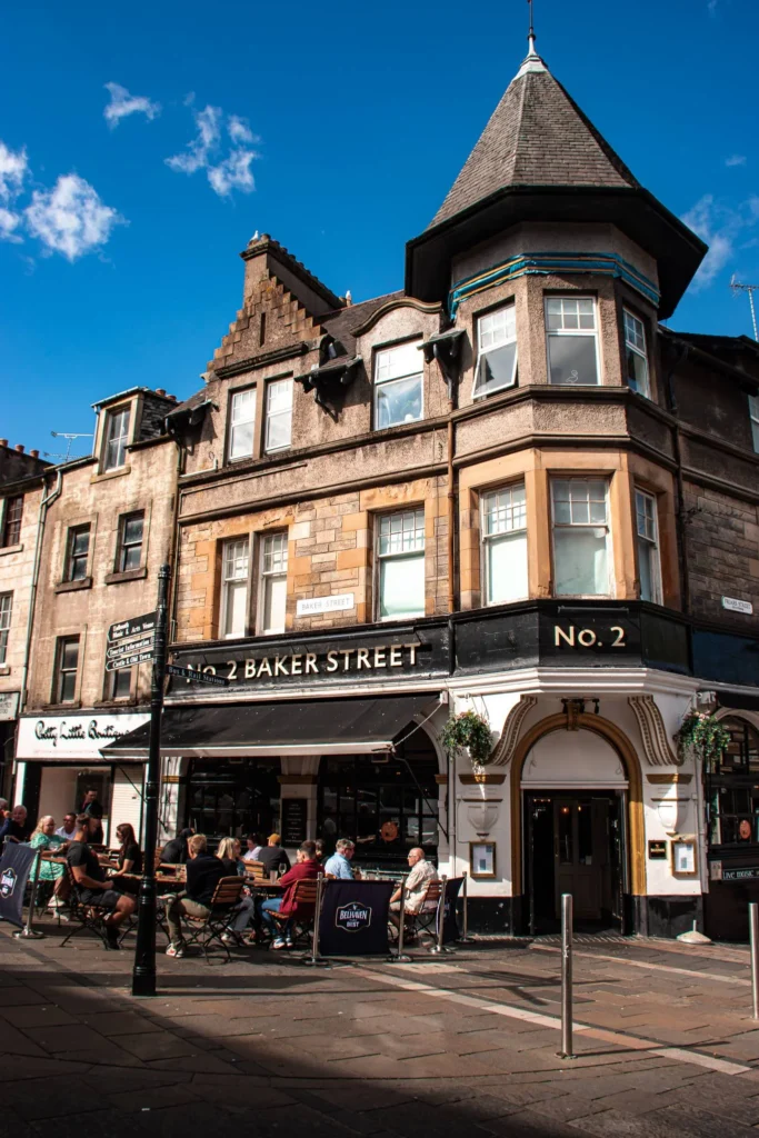 Facade of a traditional pub at the corner of a lively street in Stirling with customers on the terrace