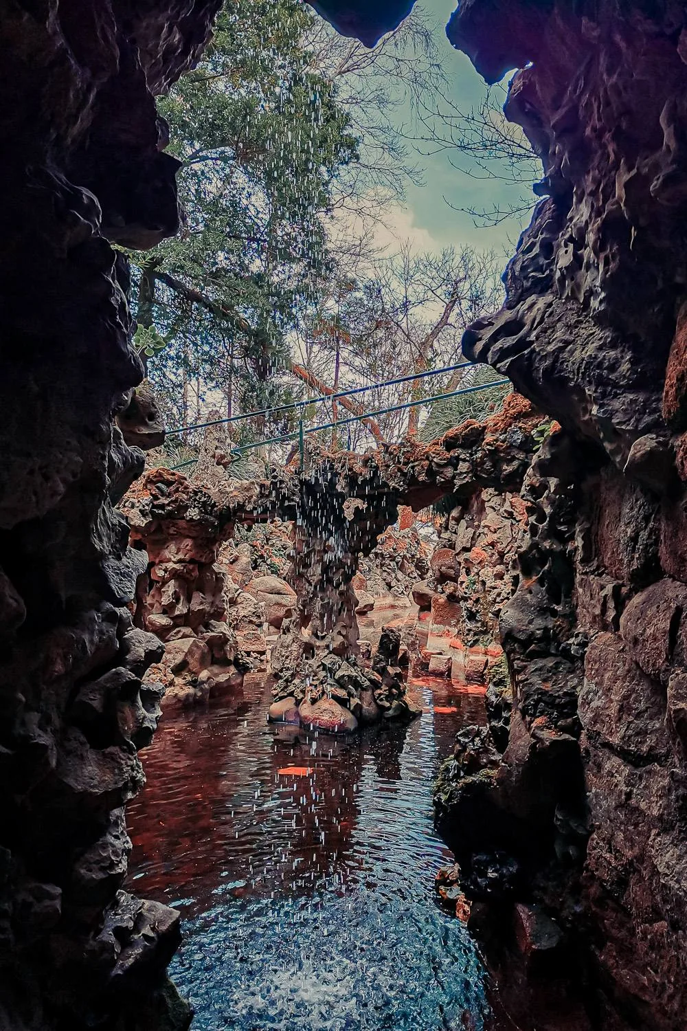 View from inside a cave of a small stone bridge and a waterfall, in the gardens of Quinta da Regaleira in Sintra, Portugal, in March 2022.