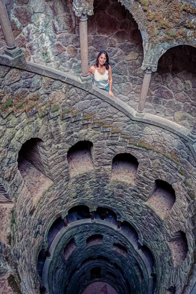 Caroline stands on a stone balcony overlooking the initiatory well of Quinta da Regaleira in Sintra, Portugal, in March 2022.