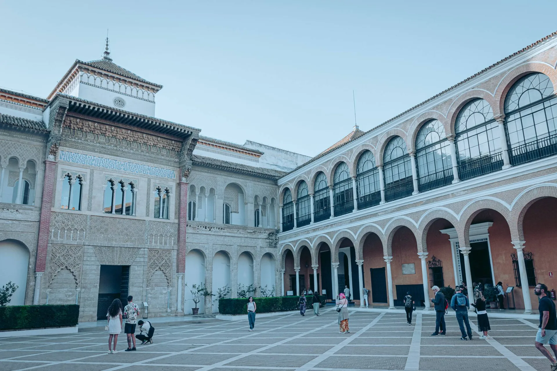 Cour intérieure du palais de l'Alcazar à Séville, architecture mudéjare et arcades visibles, quelques visiteurs dispersés dans la cour en octobre.