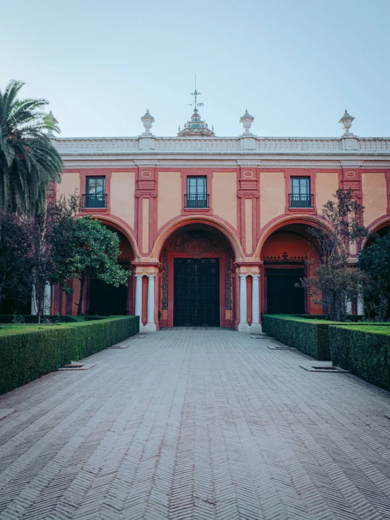 Façade principale du palais de l'Alcazar à Séville, architecture andalouse avec jardins taillés et grande porte centrale, prise en octobre 2022.